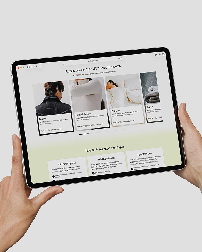 Two hands holding a tablet displaying the Lenzing website (Photo)
