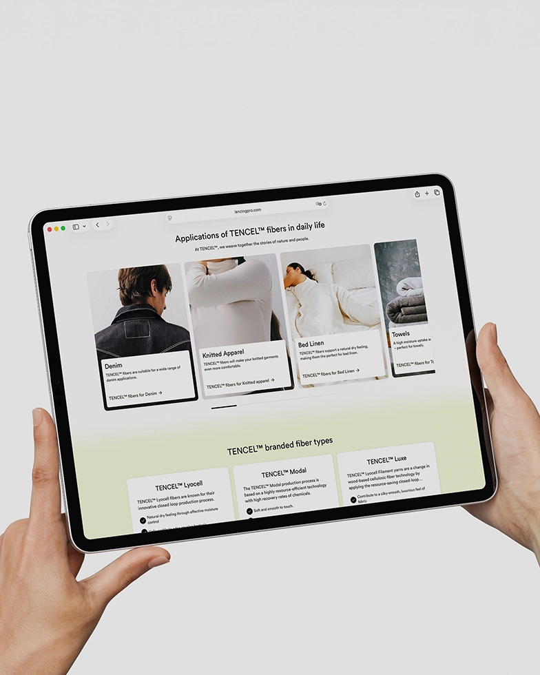 Two hands holding a tablet displaying the Lenzing website (Photo)