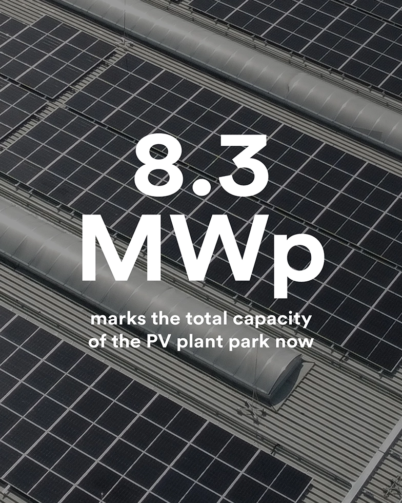 Schriftzug „8.3 MWp marks the total capacity of the PV plant park now“ vor Solaranlagen im Hintergrund (Foto)